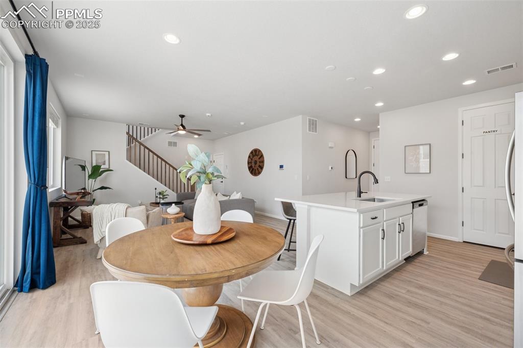 Dining area with ceiling fan, recessed lighting, light wood finished floors, and stairs