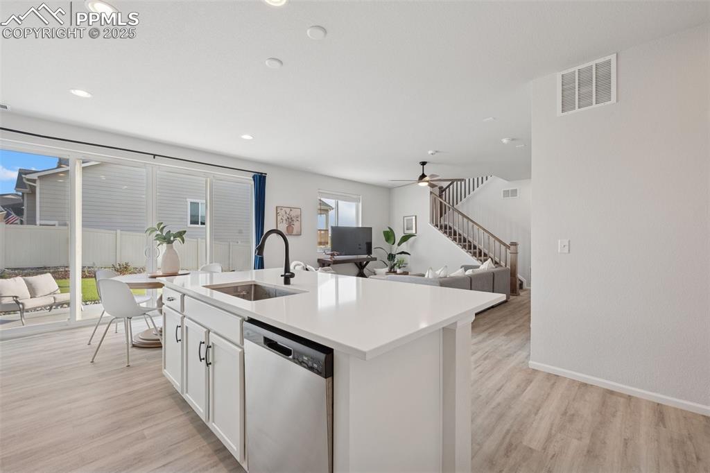 Kitchen featuring dishwasher, light wood-type flooring, white cabinets, recessed lighting, and light countertops