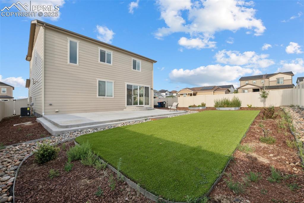 Back of property with a fenced backyard, a patio area, turf and a residential view