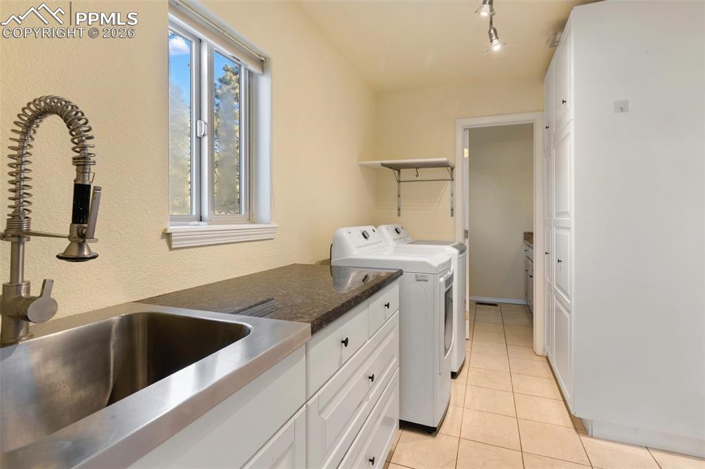 Laundry area with washer and dryer, light tile patterned floors, and track lighting