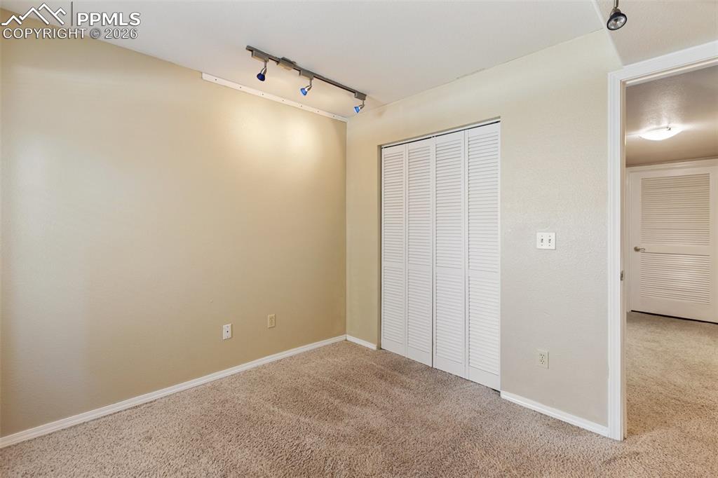 Unfurnished bedroom with rail lighting, carpet flooring, and a closet