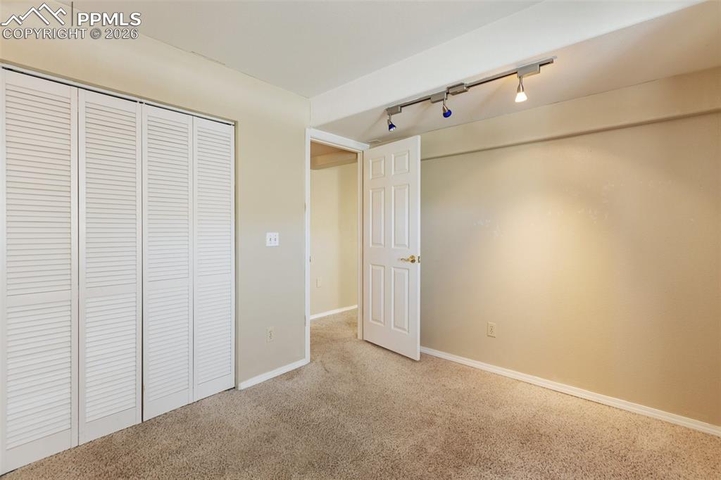 Unfurnished bedroom featuring rail lighting, carpet flooring, and a closet