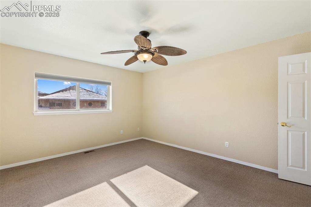 Carpeted spare room with baseboards and a ceiling fan