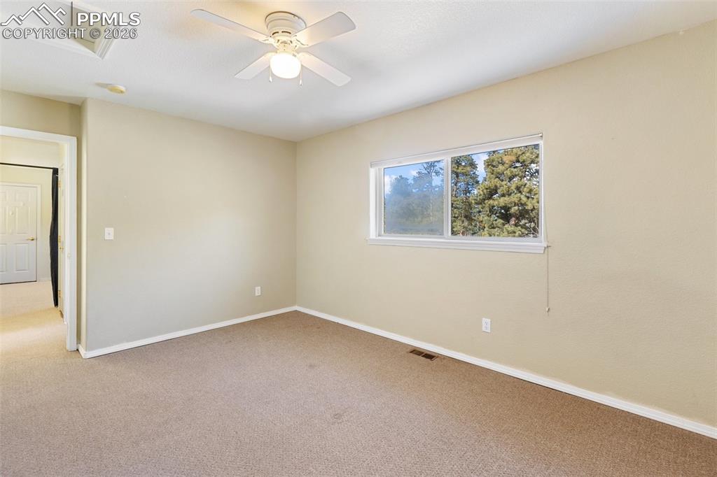 Unfurnished room featuring attic access, carpet floors, and a ceiling fan