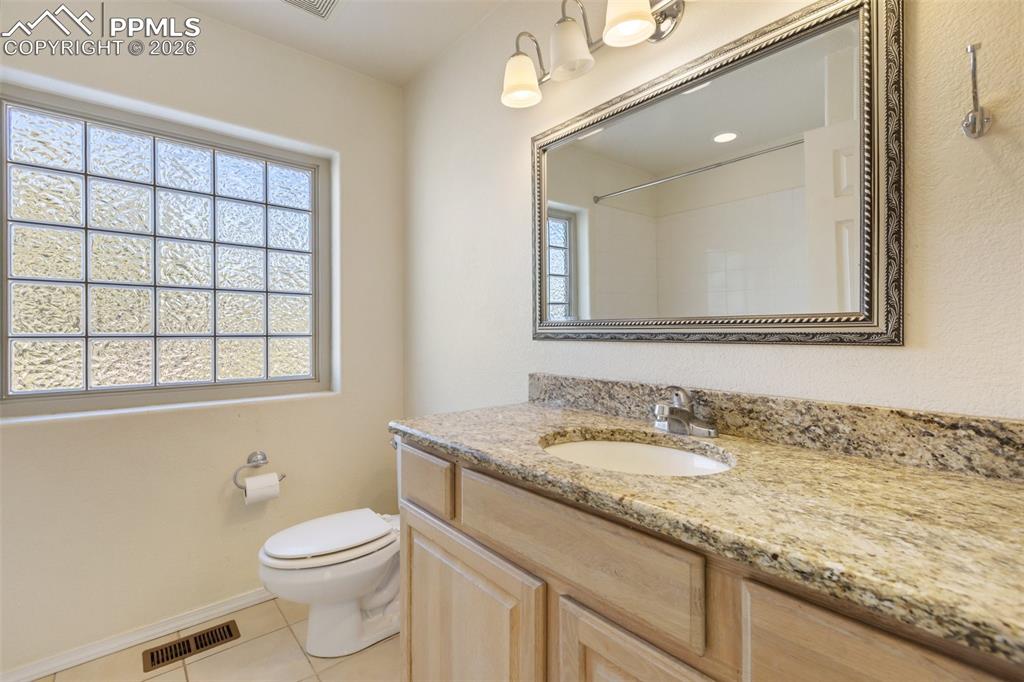 Full bathroom featuring vanity, light tile patterned flooring, plenty of natural light, and a shower