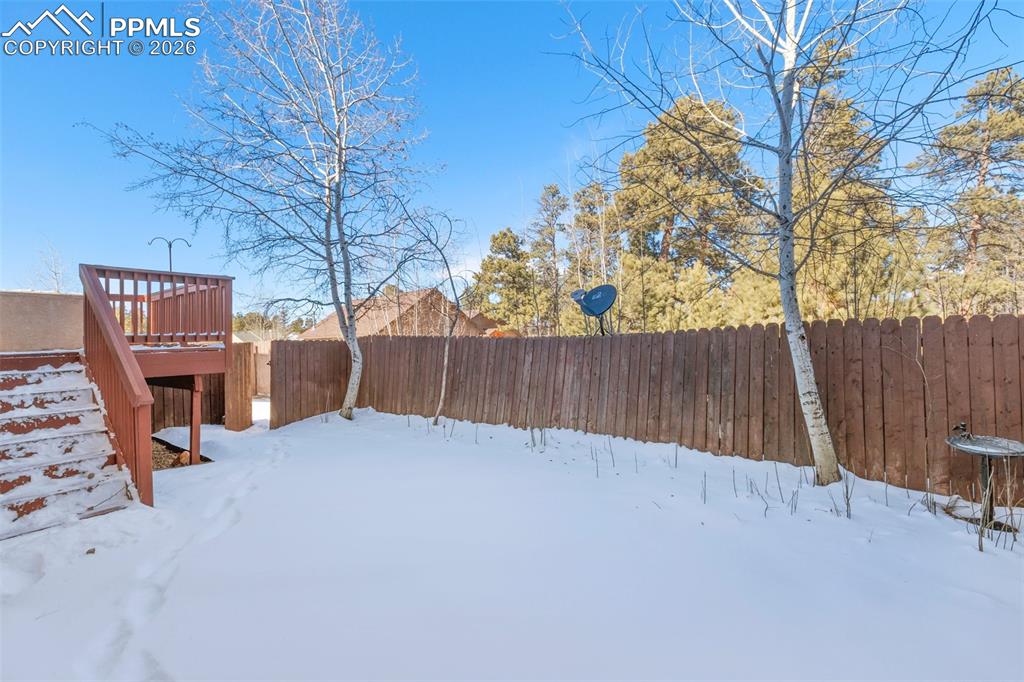 Yard covered in snow featuring a fenced backyard and a deck