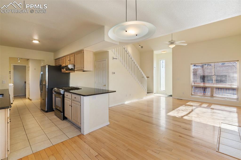 Kitchen with open floor plan, gas stove, light wood finished floors, ceiling fan, and decorative light fixtures
