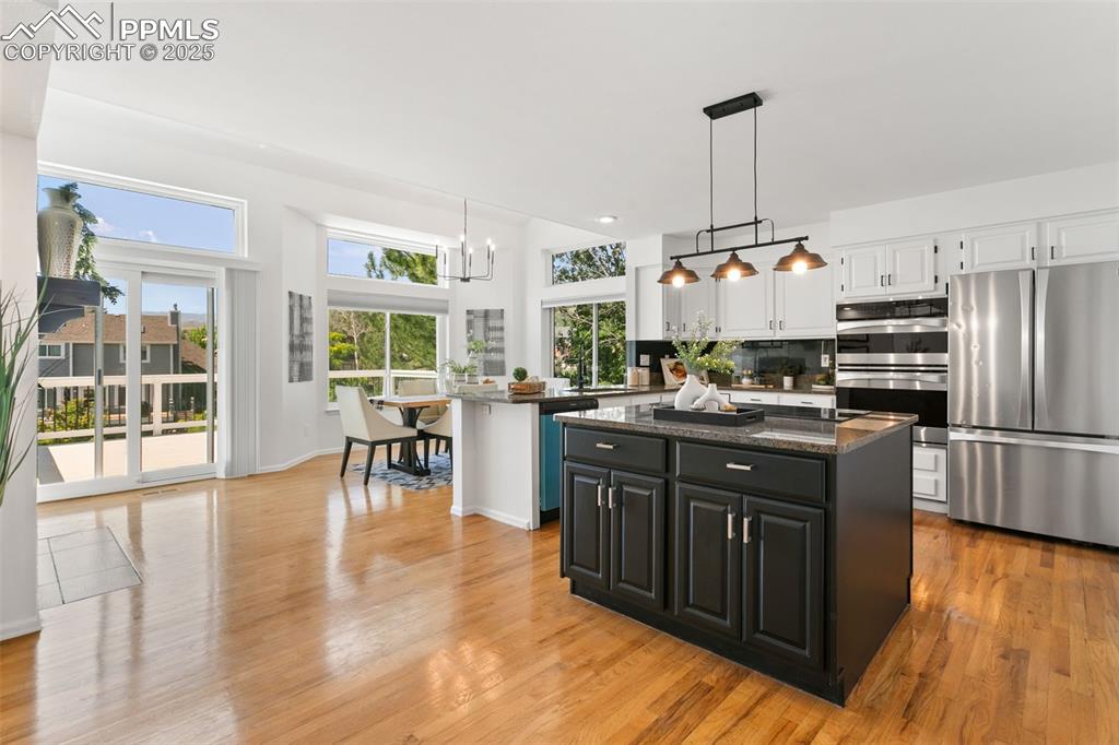 Kitchen featuring stainless steel appliances, white cabinets, a kitchen island, and light wood-style floors