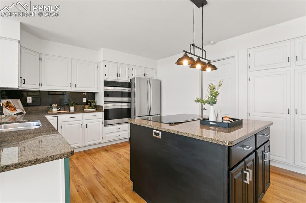 Kitchen with white cabinetry, light wood-style floors, a center island, and appliances with stainless steel finishes