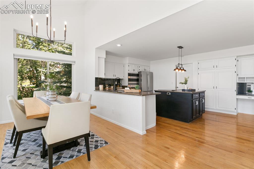 Dining space with a chandelier, light wood-style flooring, recessed lighting, and a high ceiling
