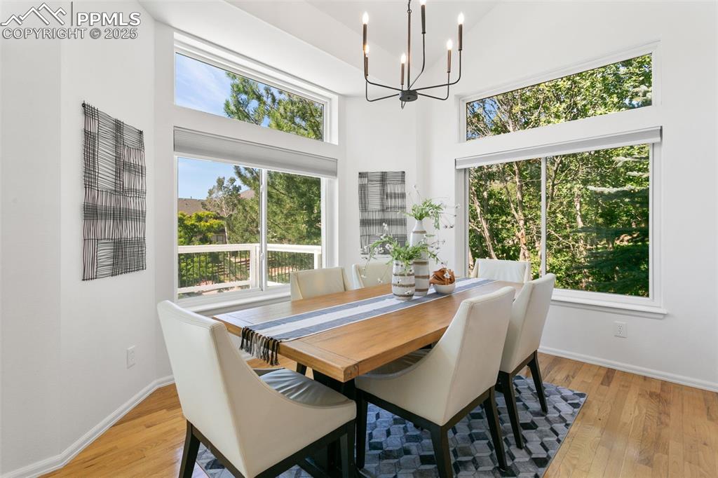 Dining area featuring light wood-style flooring, a chandelier, and a towering ceiling