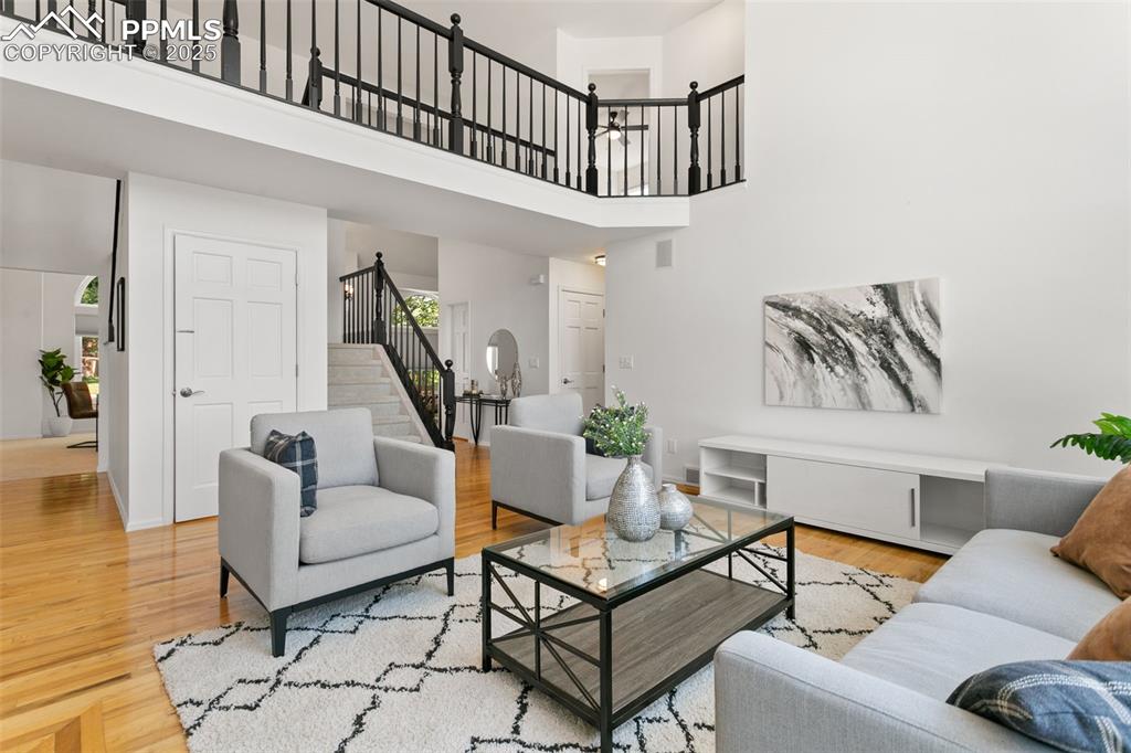 Living room featuring a towering ceiling, wood finished floors, and stairs