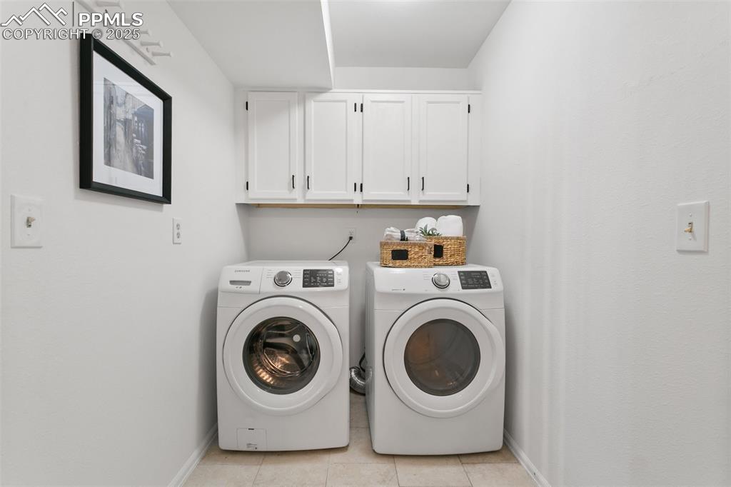 Laundry area featuring cabinet space, independent washer and dryer, and light tile patterned flooring
