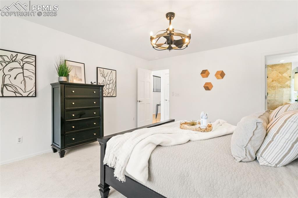 Bedroom with light carpet and a chandelier