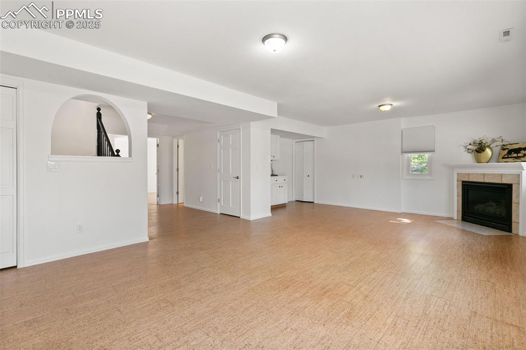Unfurnished living room with a tile fireplace and baseboards