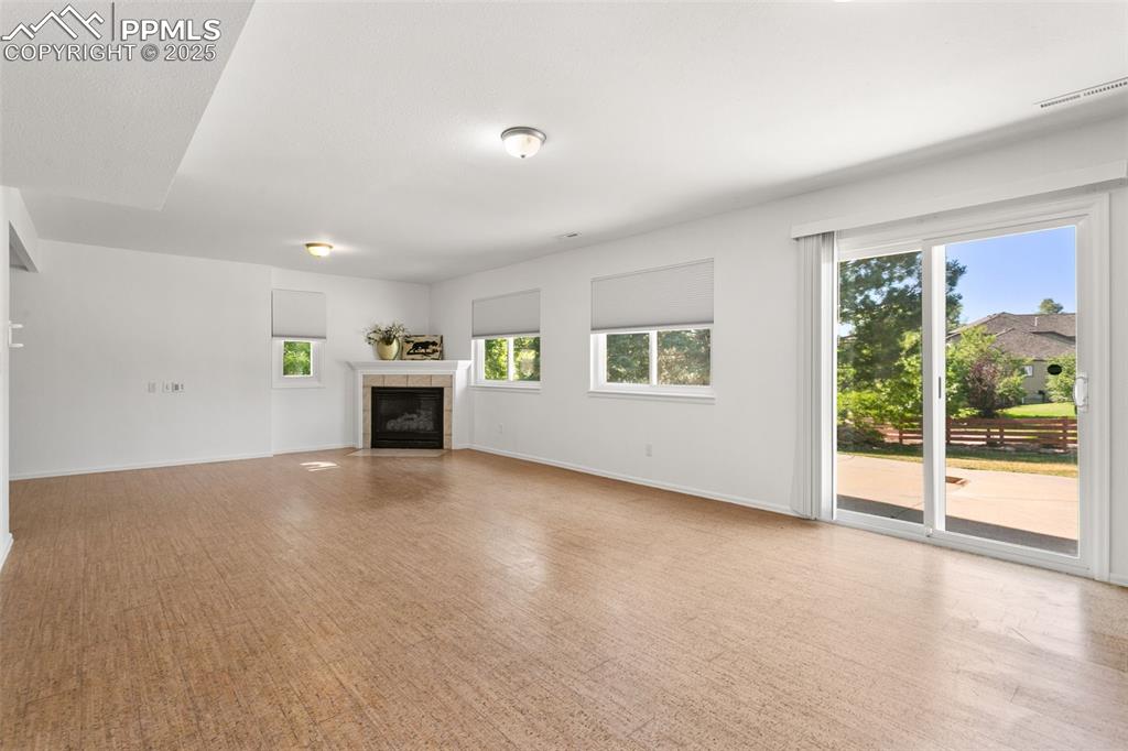 Unfurnished living room featuring a tile fireplace and baseboards