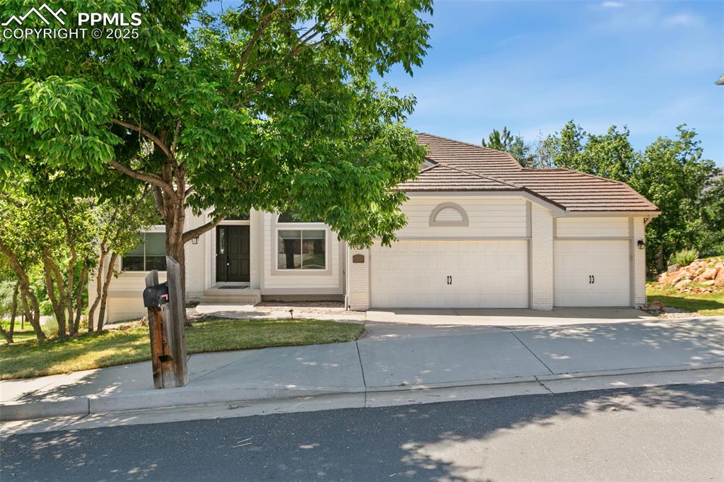 Obstructed view of property with brick siding, a tile roof, an attached garage, and concrete driveway