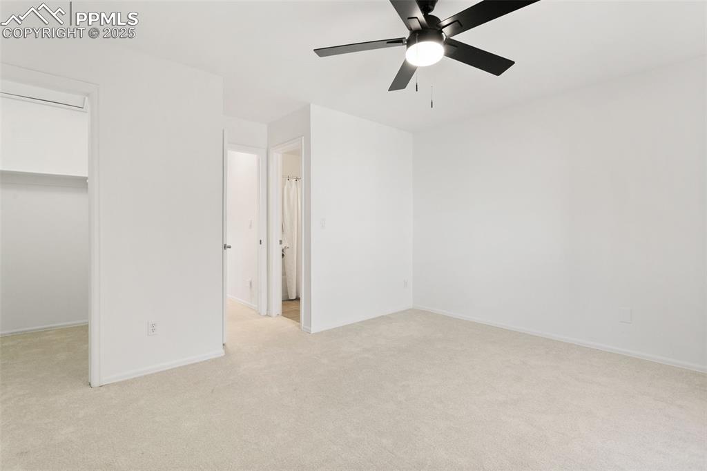 Unfurnished bedroom featuring light carpet, ceiling fan, and a spacious closet