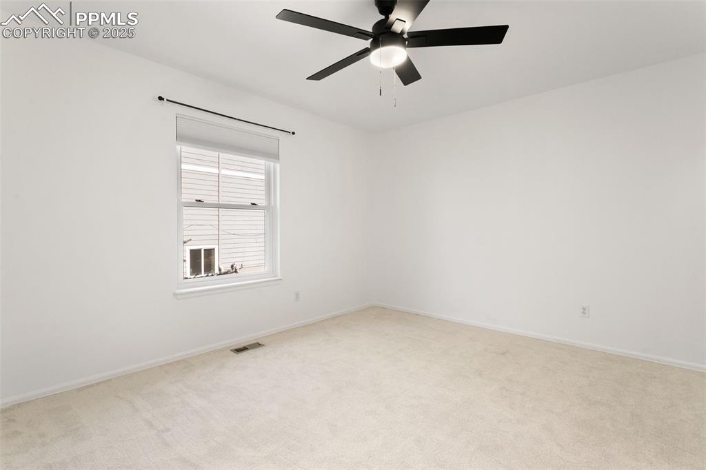 Empty room with carpet flooring and a ceiling fan