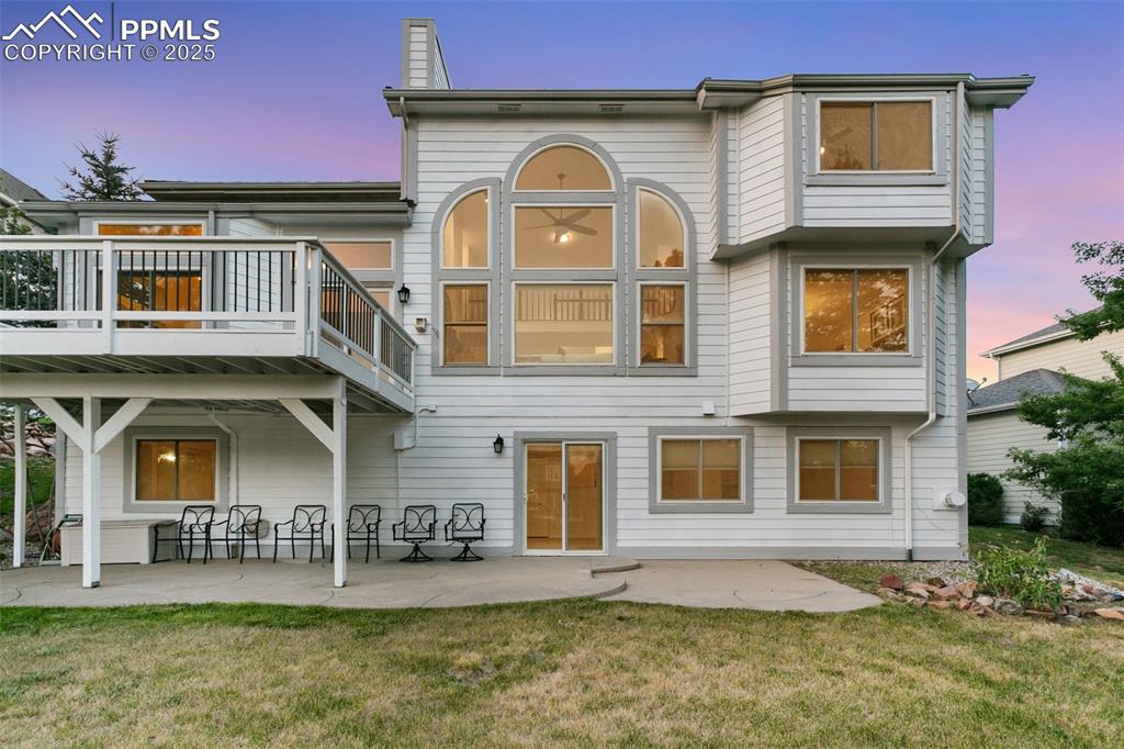 Rear view of house with a lawn, a patio, and a chimney