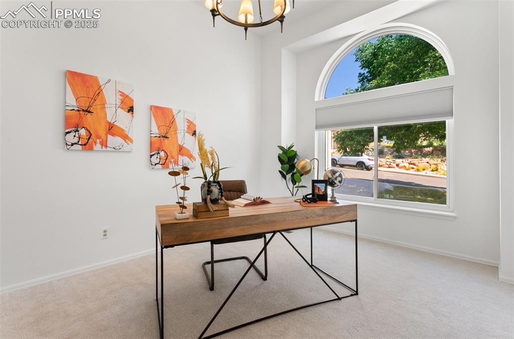 Carpeted office featuring a chandelier and baseboards