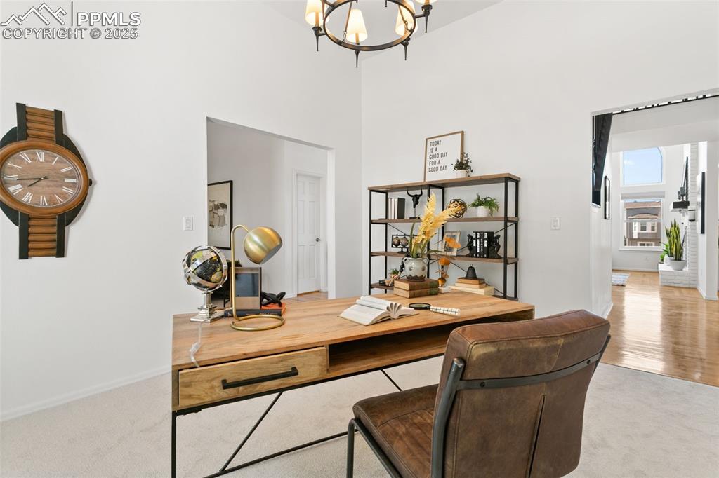 Home office with a chandelier, carpet flooring, and a high ceiling