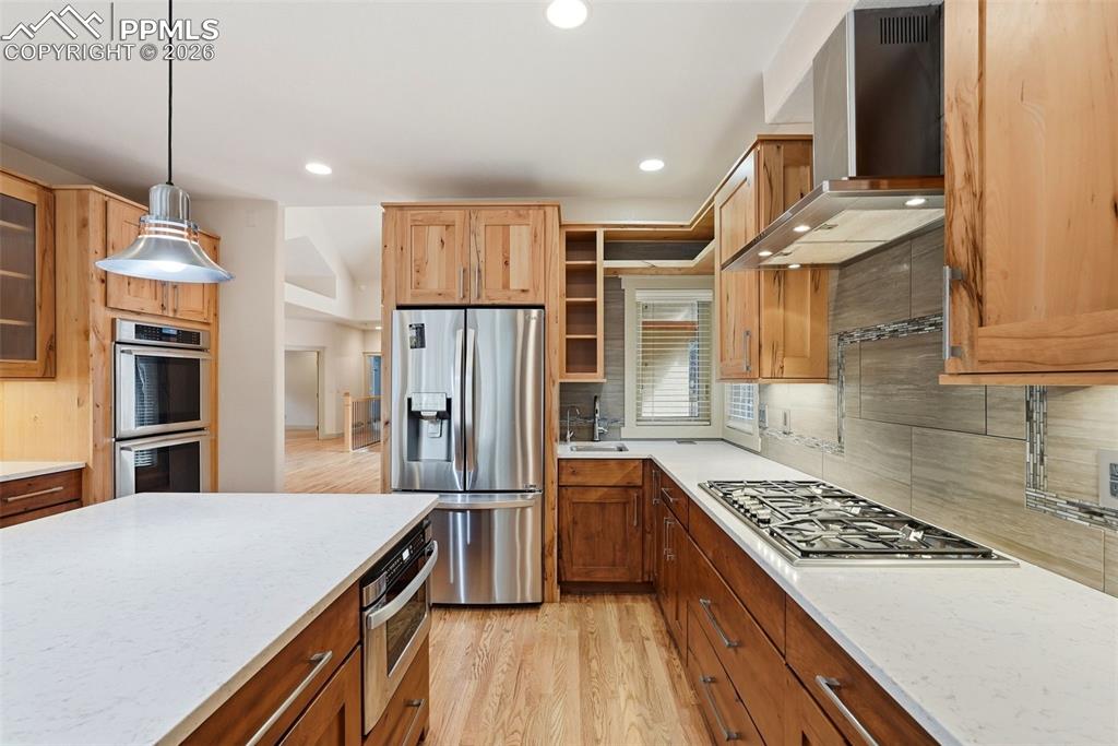 Kitchen with stainless steel appliances, light wood flooring, stone counters, and glass fronted cabinets-Top of the line appliances