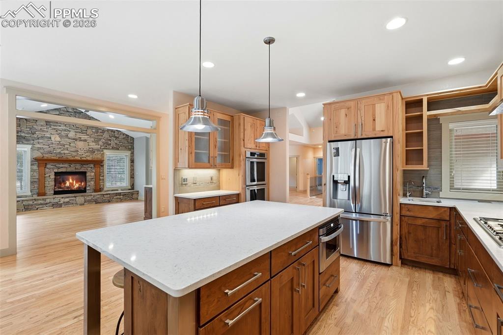 Kitchen featuring a center island, stainless steel appliances, glass insert cabinets, light wood floors