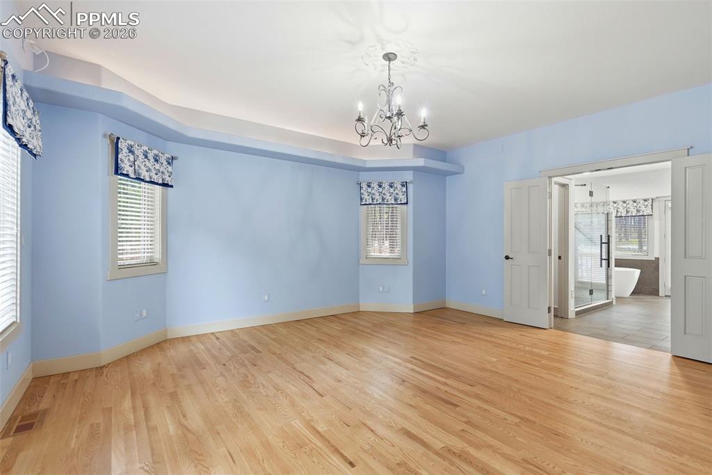 Primary Bedroom suite with lot of natural light, hanging lights, wood floors, fireplace and martini balcony