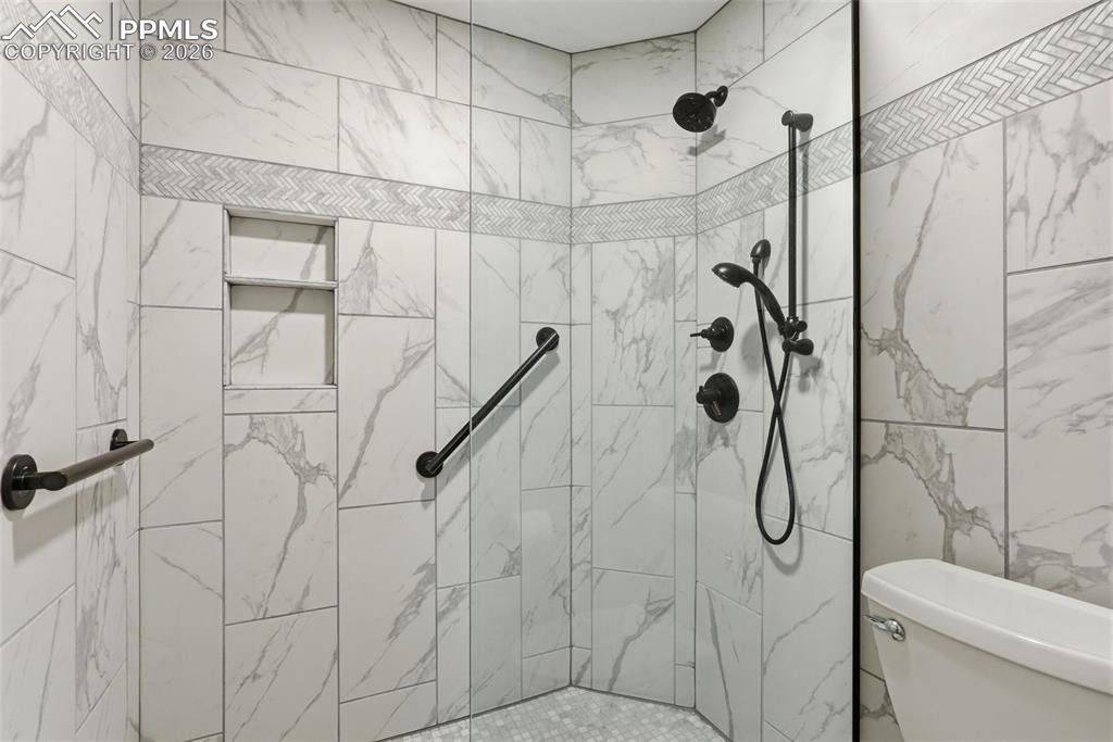 Full bath featuring toilet and tiled shower