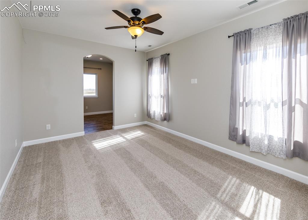 Spacious primary bedroom with arched door detail with a peek into the bonus room.
