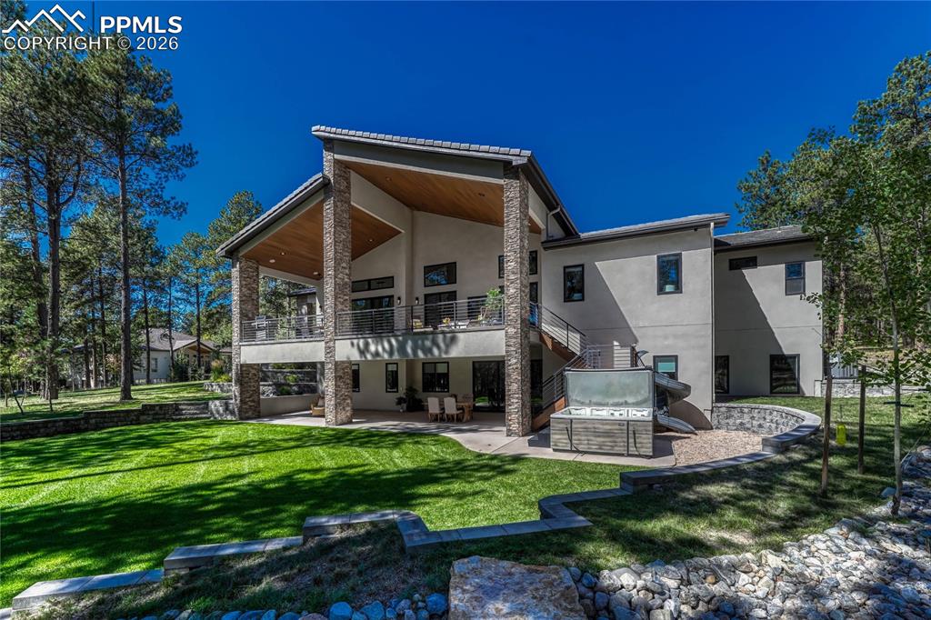 Back of property with a patio area, stucco siding, a lawn, and a balcony
