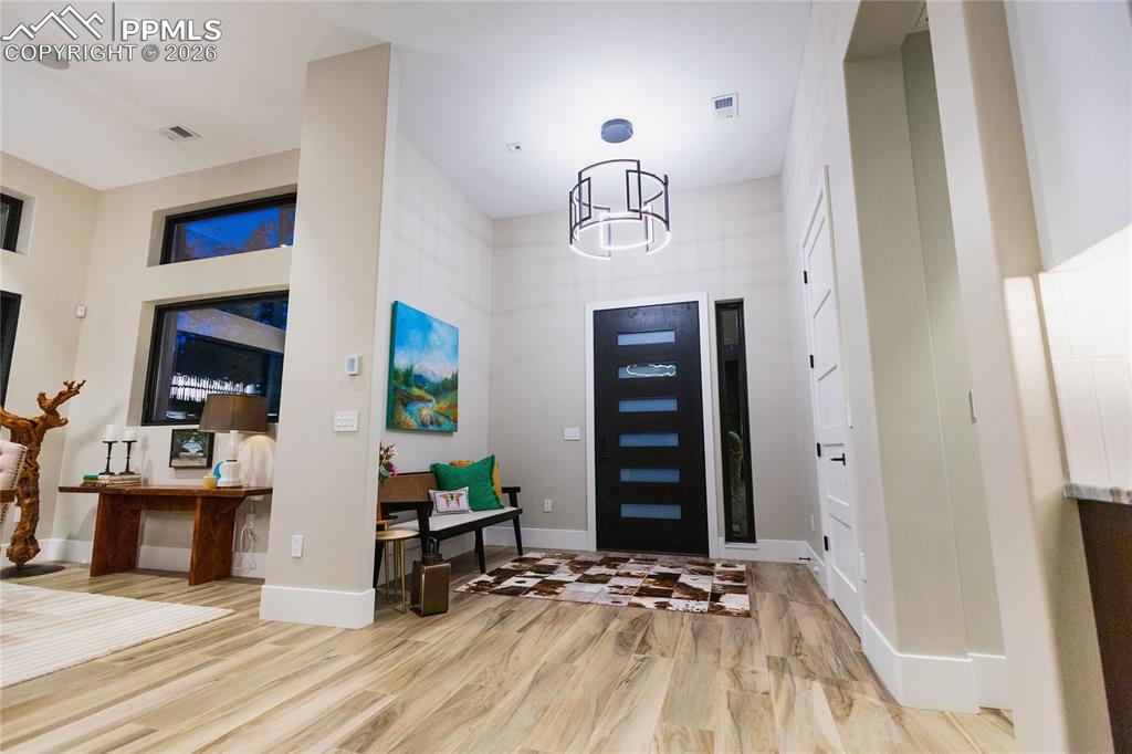 Entrance foyer with light wood-style floors and suspended lighting