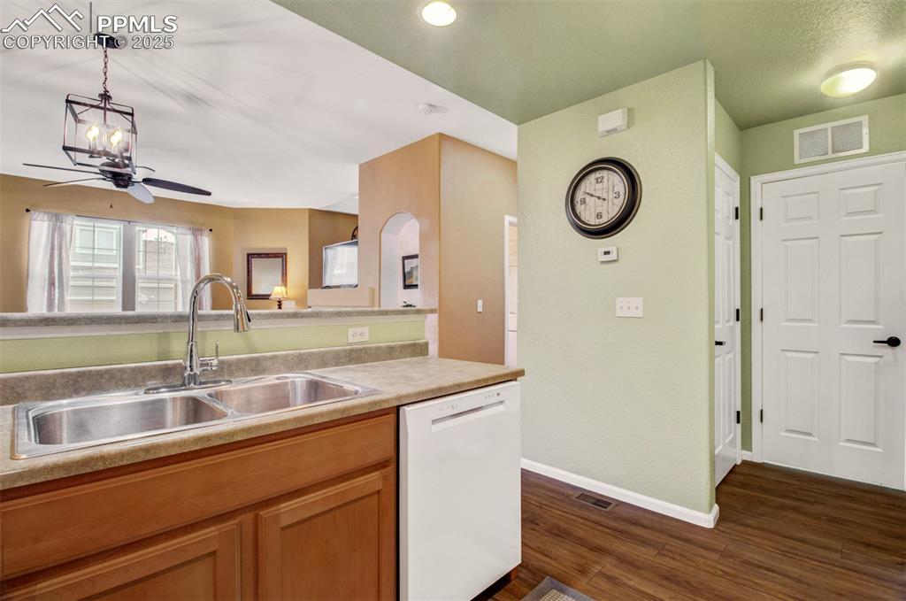 Kitchen featuring new dishwasher, light countertops, new flooring, hanging light fixtures, brown cabinetry and a new faucet
