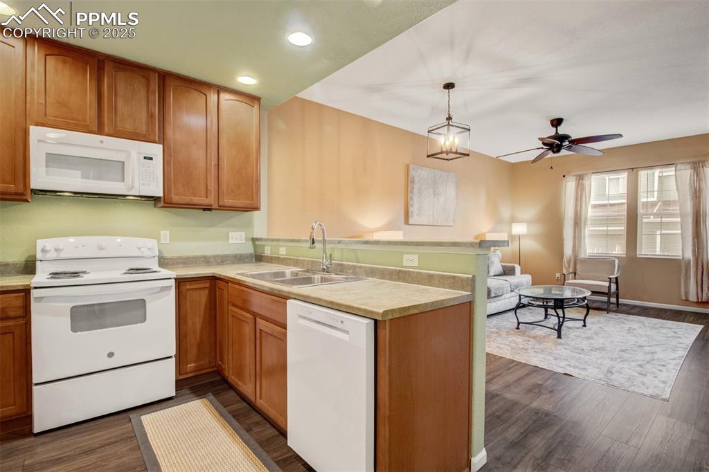 Kitchen with white appliances, new flooring, fresh paint, recessed lighting, brown cabinetry, pendant lighting and a new dishwasher