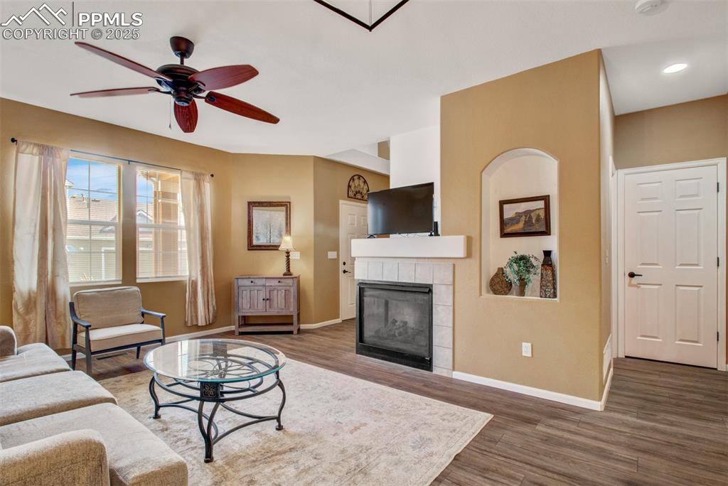 Living area featuring a fireplace, new flooring, and ceiling fan