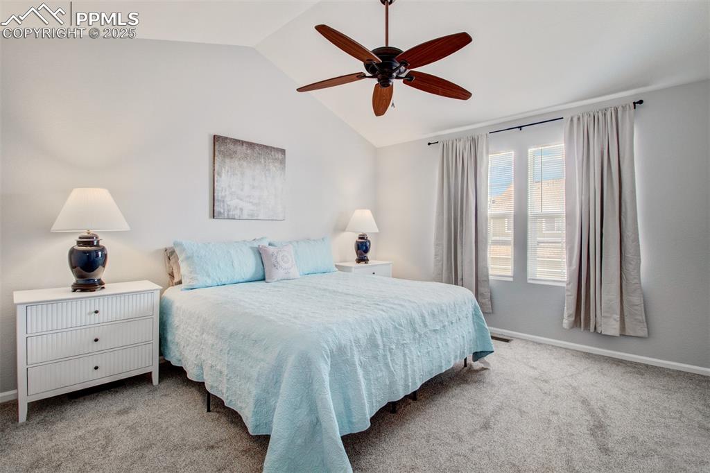 Primary bedroom featuring vaulted ceiling, new carpeted floors, ceiling fan, and window coverings. Bed is new and maybe slept in 10 times or less :~)