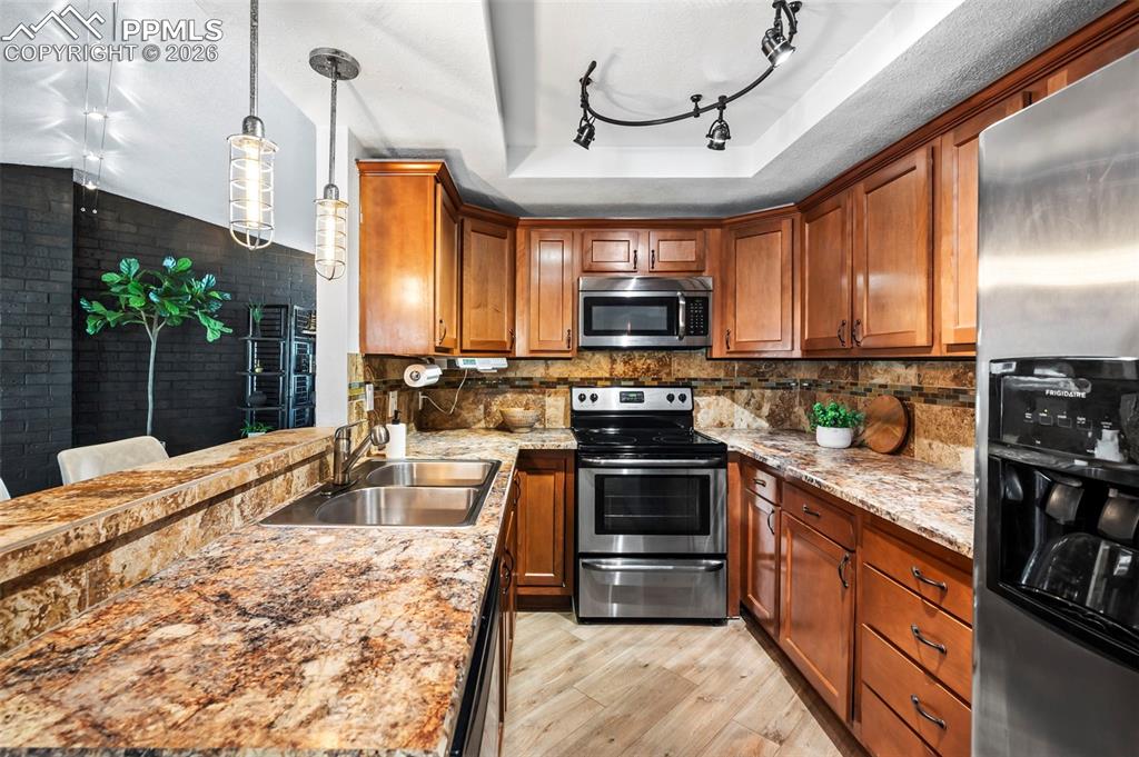 Rich wood cabinetry brings warmth, depth, and a sense of timeless craftsmanship. Stainless steel appliances integrate seamlessly for a refined, functional finish, and sculptural lighting elements add subtle drama and architectural interest