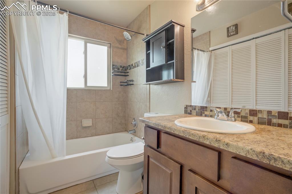 Full bathroom with a closet, vanity, shower / tub combo, decorative backsplash, and a textured wall