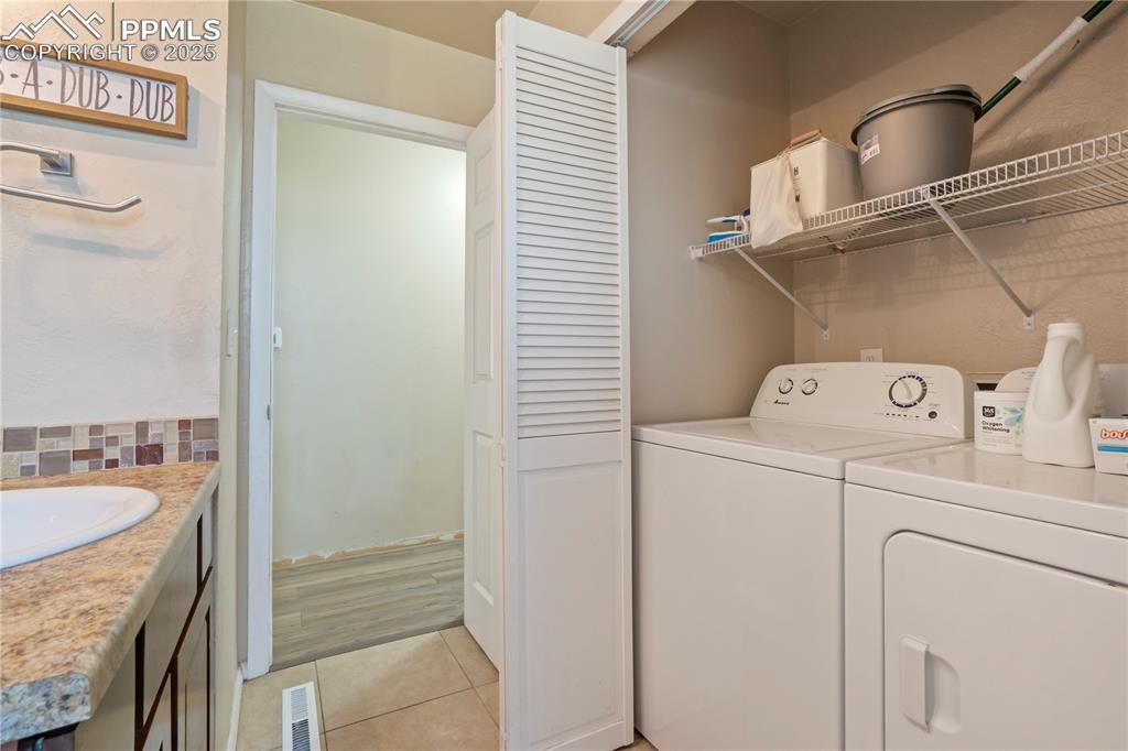 Laundry room with light tile patterned floors and washing machine and clothes dryer