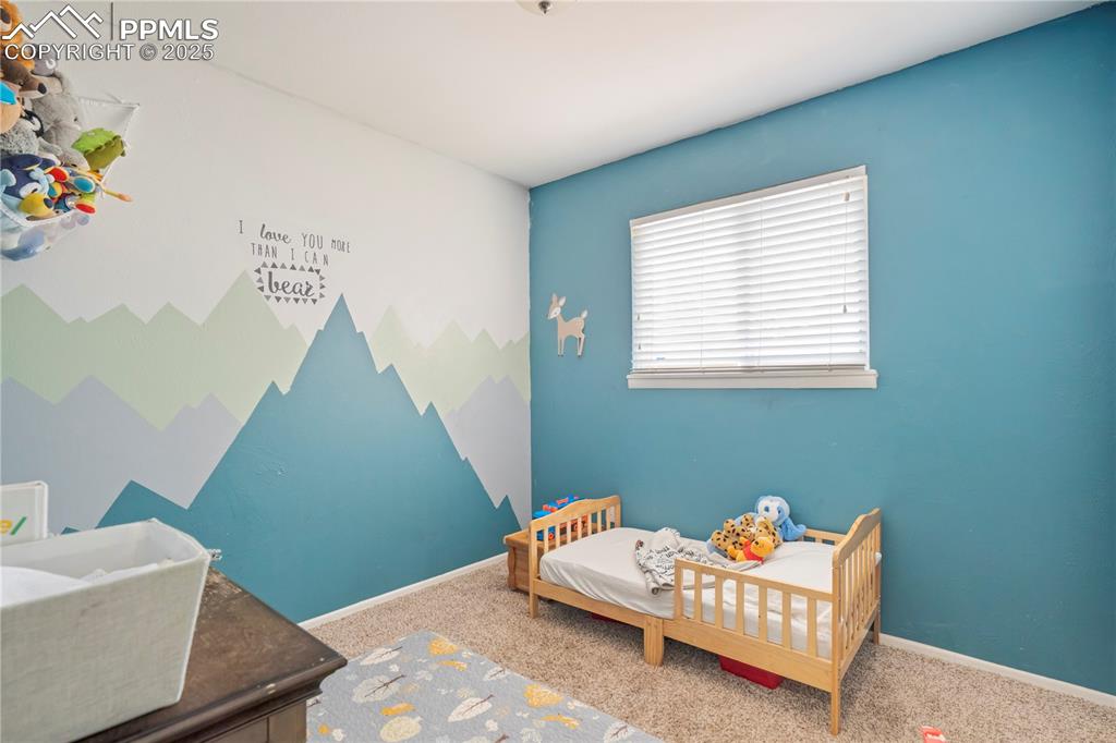 Carpeted bedroom featuring a nursery area and an accent wall