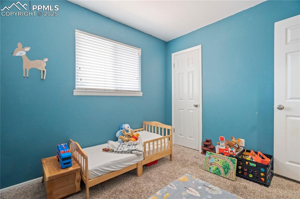 Carpeted bedroom featuring a nursery area
