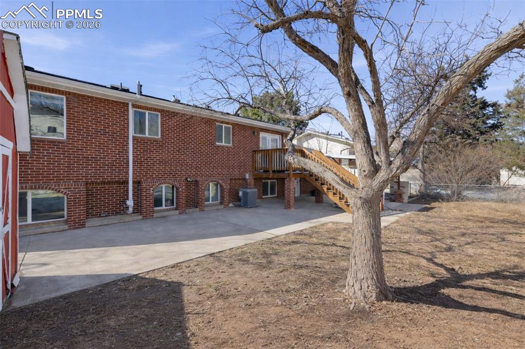 Rear view of property featuring brick siding and a deck