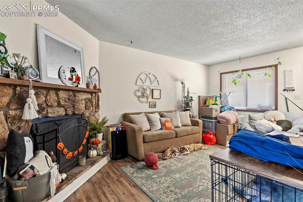 Living room featuring a textured ceiling, a fireplace, and wood finished floors