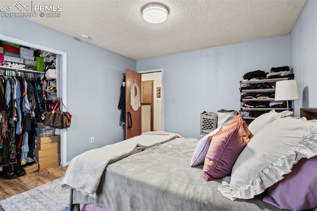 Bedroom featuring a textured ceiling, a closet, and wood finished floors