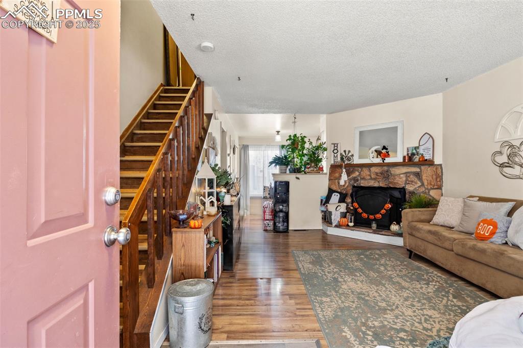 Living area featuring wood finished floors, a textured ceiling, a fireplace, and stairway