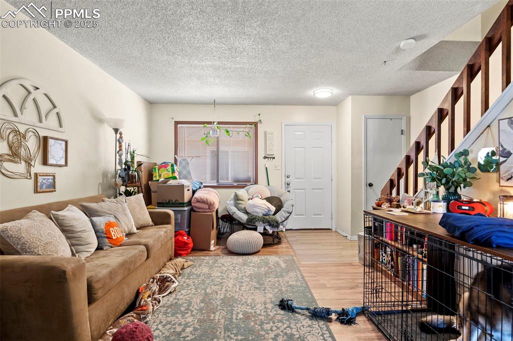 Living room with stairway, a textured ceiling, and light wood-type flooring