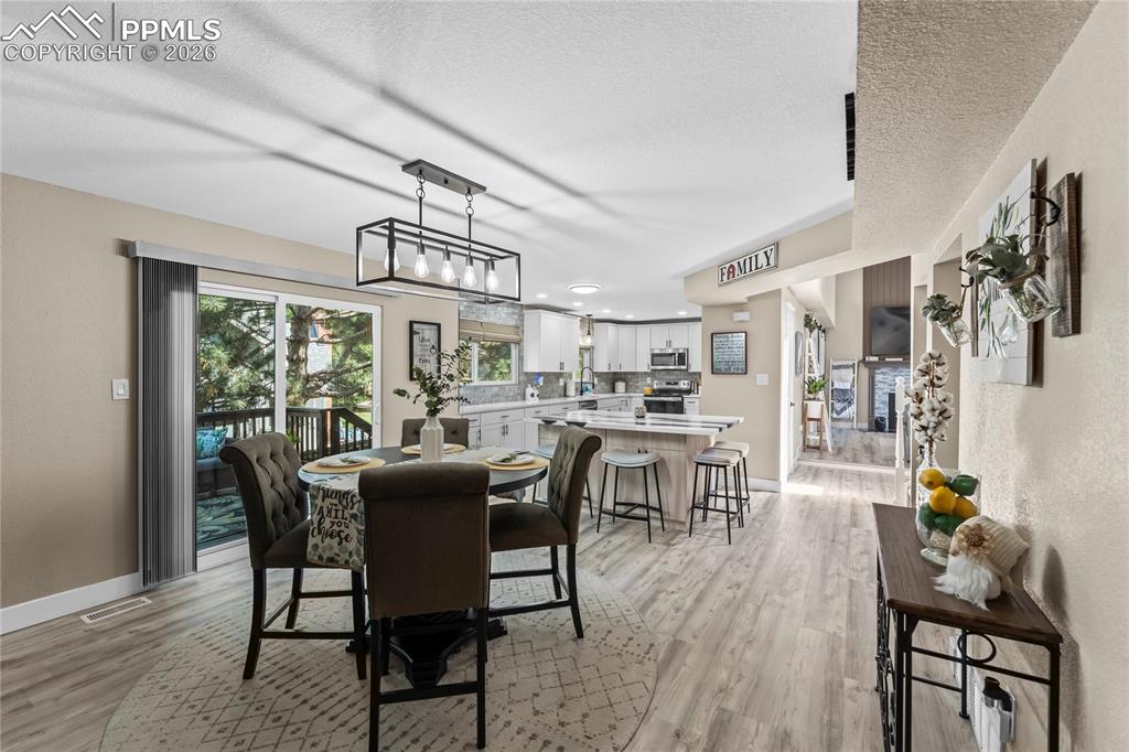 Dining area with a textured ceiling, light wood finished floors, and recessed lighting