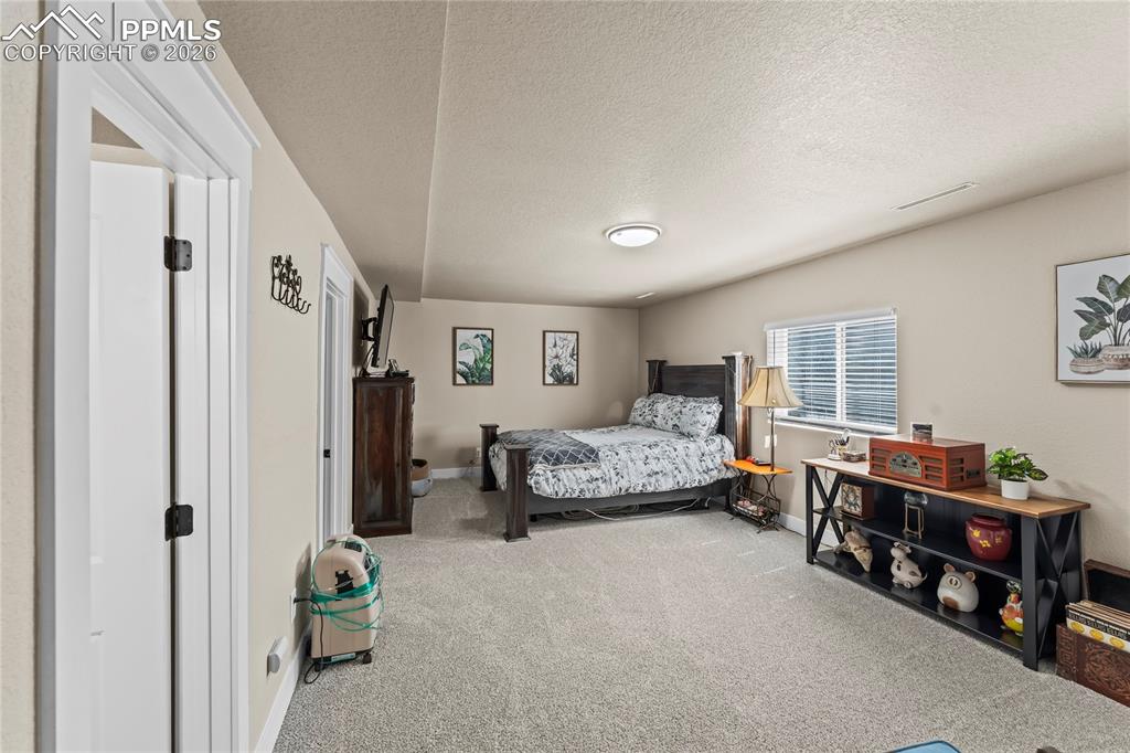 Carpeted bedroom featuring a textured ceiling and baseboards