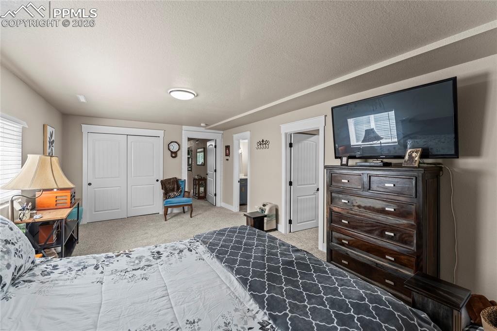 Bedroom with light colored carpet, a textured ceiling, and a closet